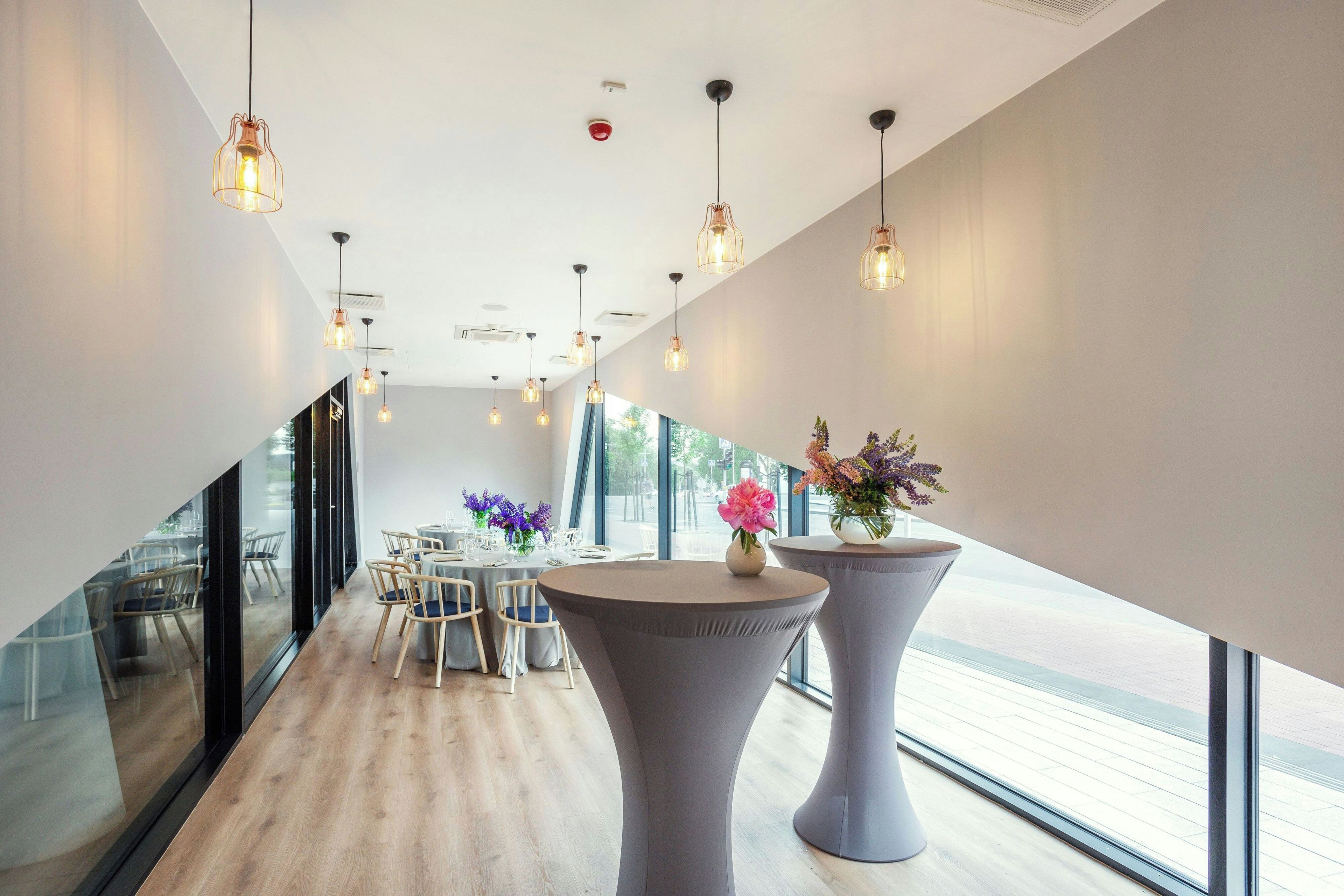 A modern interior with a dining area, large windows, and pendant lighting.