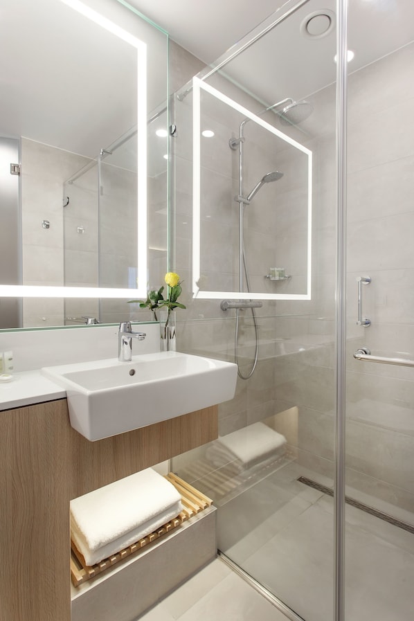 A modern bathroom with a glass-enclosed shower, a large mirror, and a wooden vanity. - Courtyard by Marriott Vilnius City Center (Vilnius)
