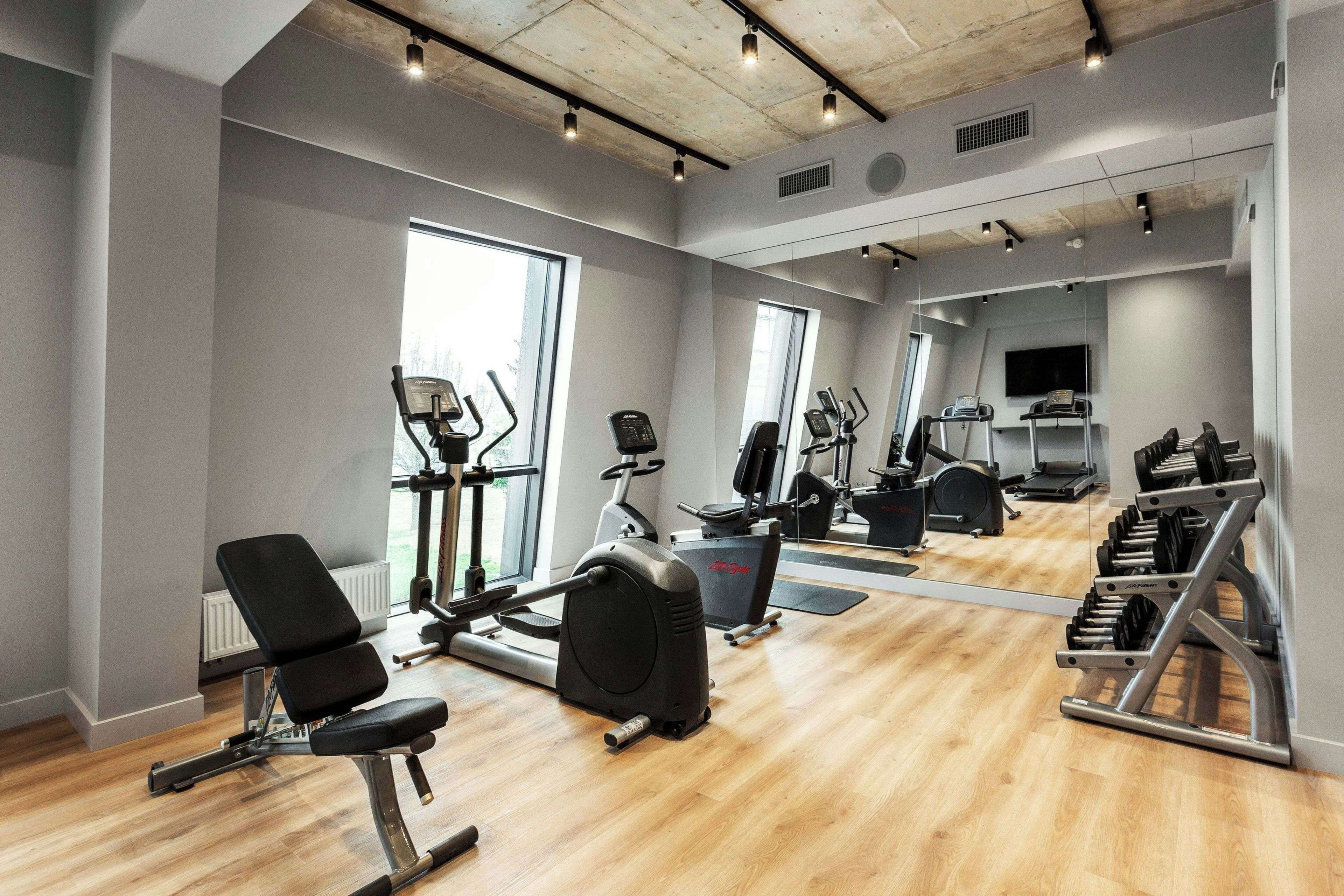 Ett modernt gym med konditionsmaskiner, fria vikter och en vägg full av speglar.