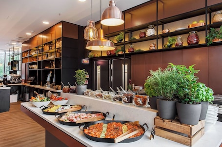 A buffet setup with various dishes and potted plants.