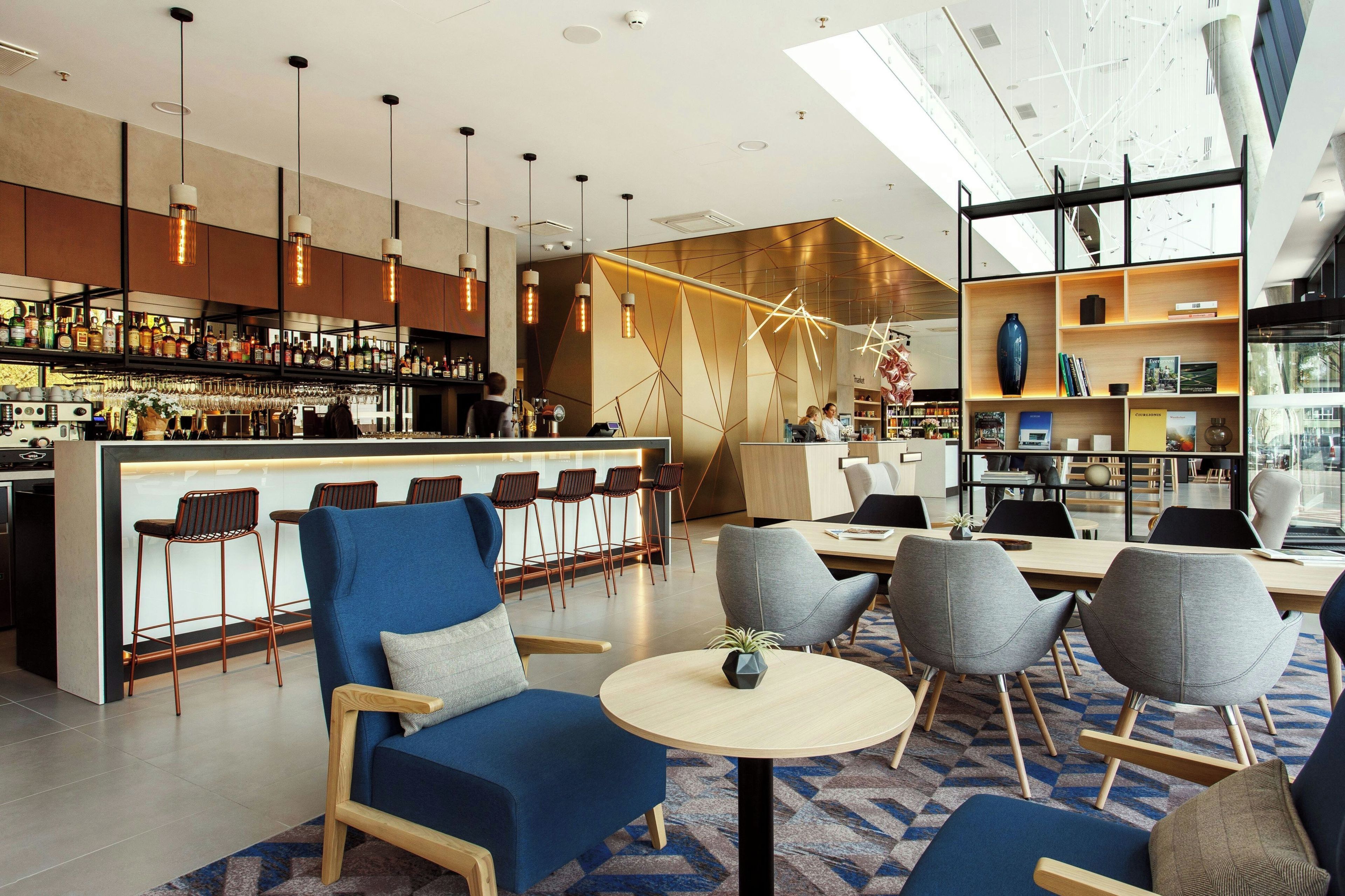 A modern bar area with a bar counter, seating, and a variety of bottles and glasses.