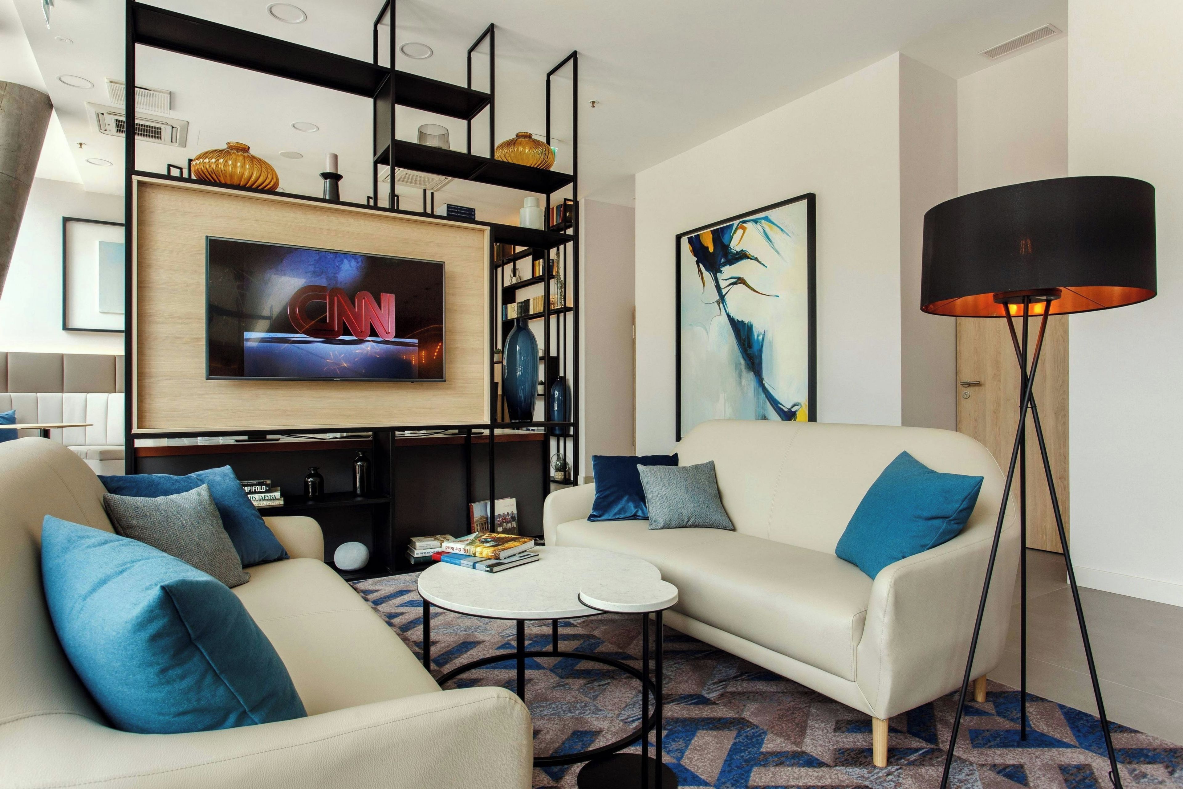 A modern living room with a sofa, coffee table, and a TV mounted on a wooden panel.