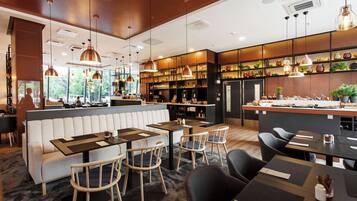 Un intérieur de restaurant moderne, avec un bar, des espaces aménagés pour s’asseoir et une vue sur l’extérieur.