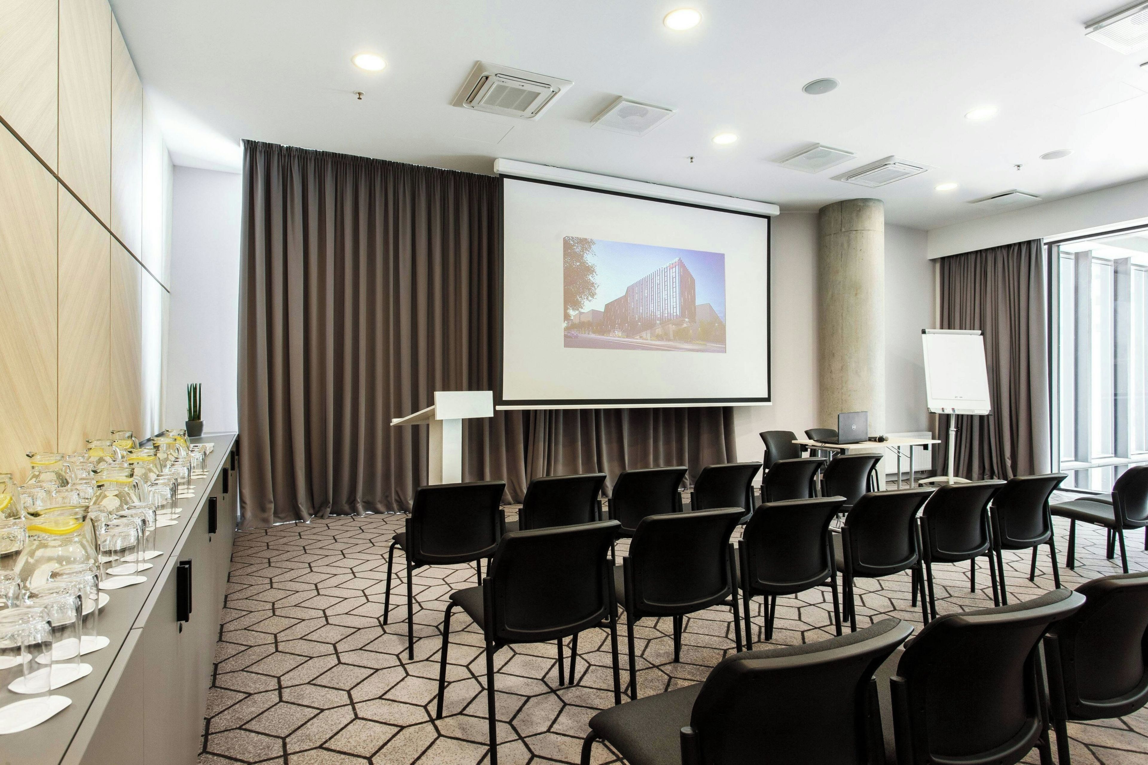 A conference room with a long table, chairs, a projector screen, and a whiteboard.