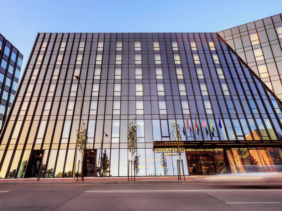 Un hotel moderno con fachada de vidrio, entrada visible y un letrero que indica que es un Courtyard Marriott.
