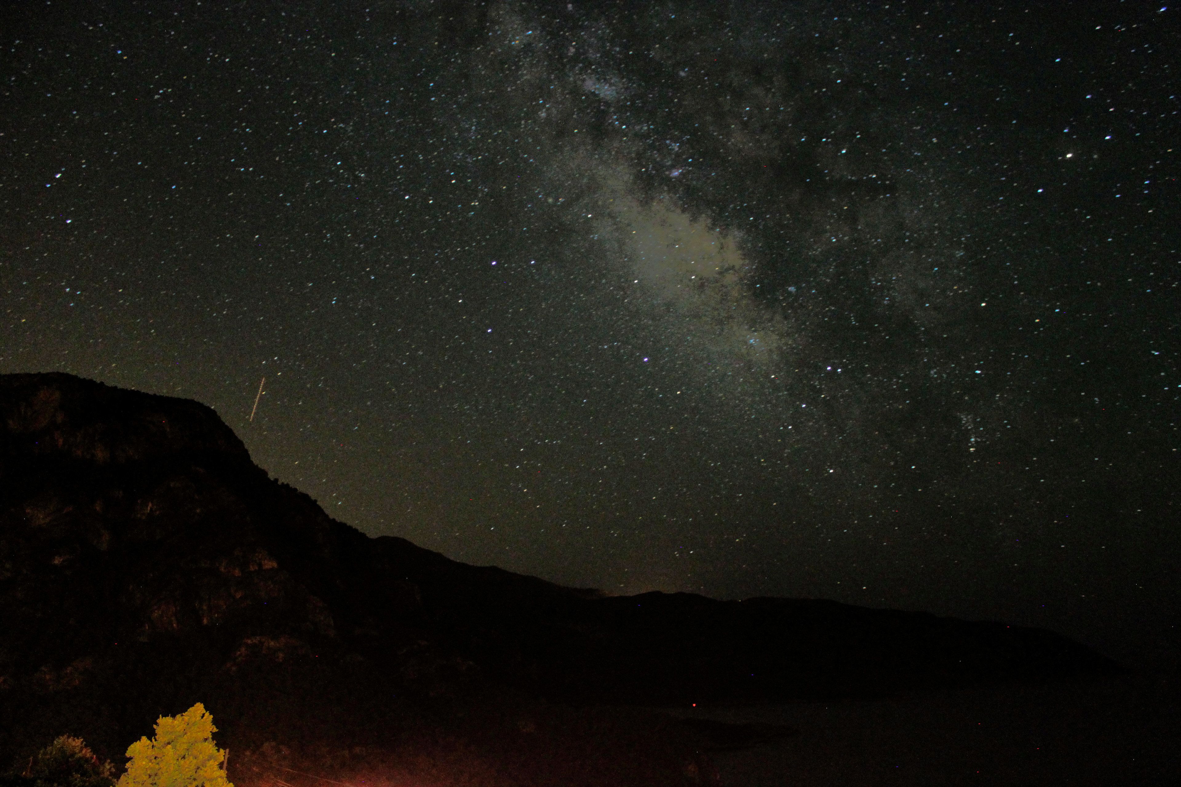 A night sky filled with stars and the Milky Way over a mountainous landscape.