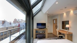 Une chambre d’hôtel moderne dotée d’une grande fenêtre, d’un téléviseur à écran plat, d’un bureau et d’un lit.