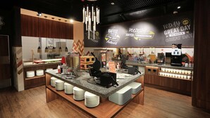 L’intérieur d’un café moderne présente un îlot central, un espace dédié aux baristas et un mur orné de citations inspirantes.