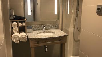 Um banheiro moderno com pia de granito, vaso sanitário e box de vidro.