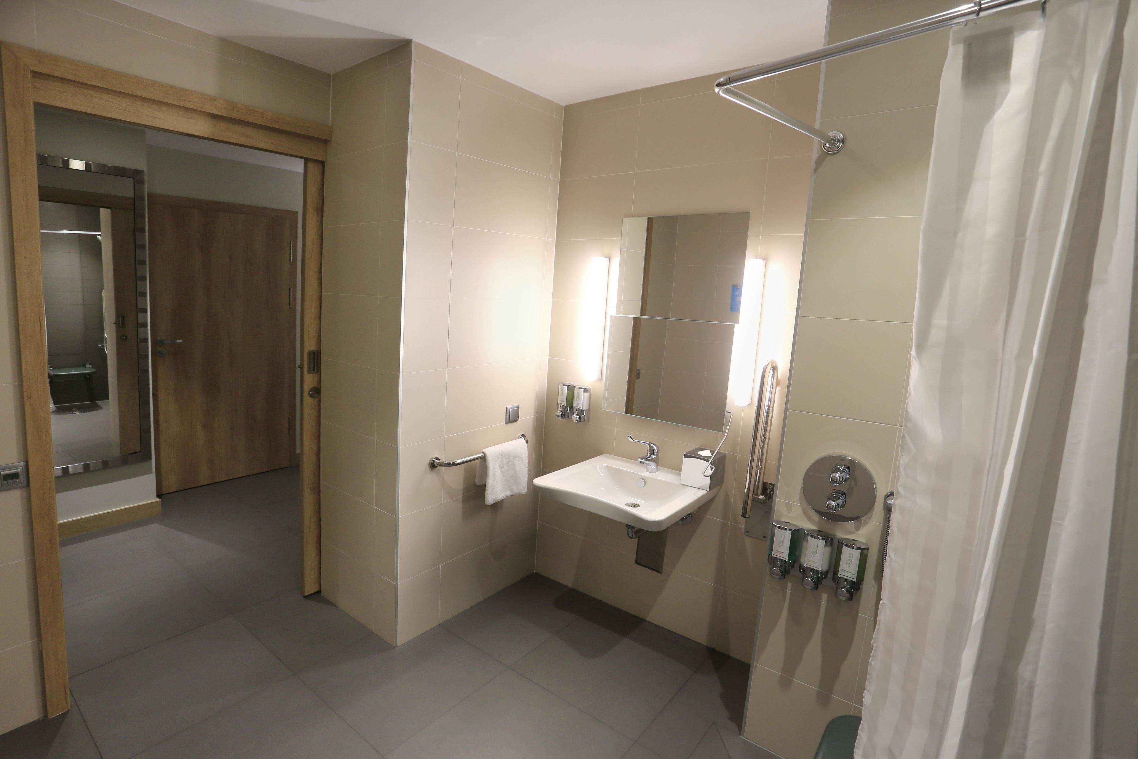 Et moderne badeværelse med vask, spejl, bruser og toilet.