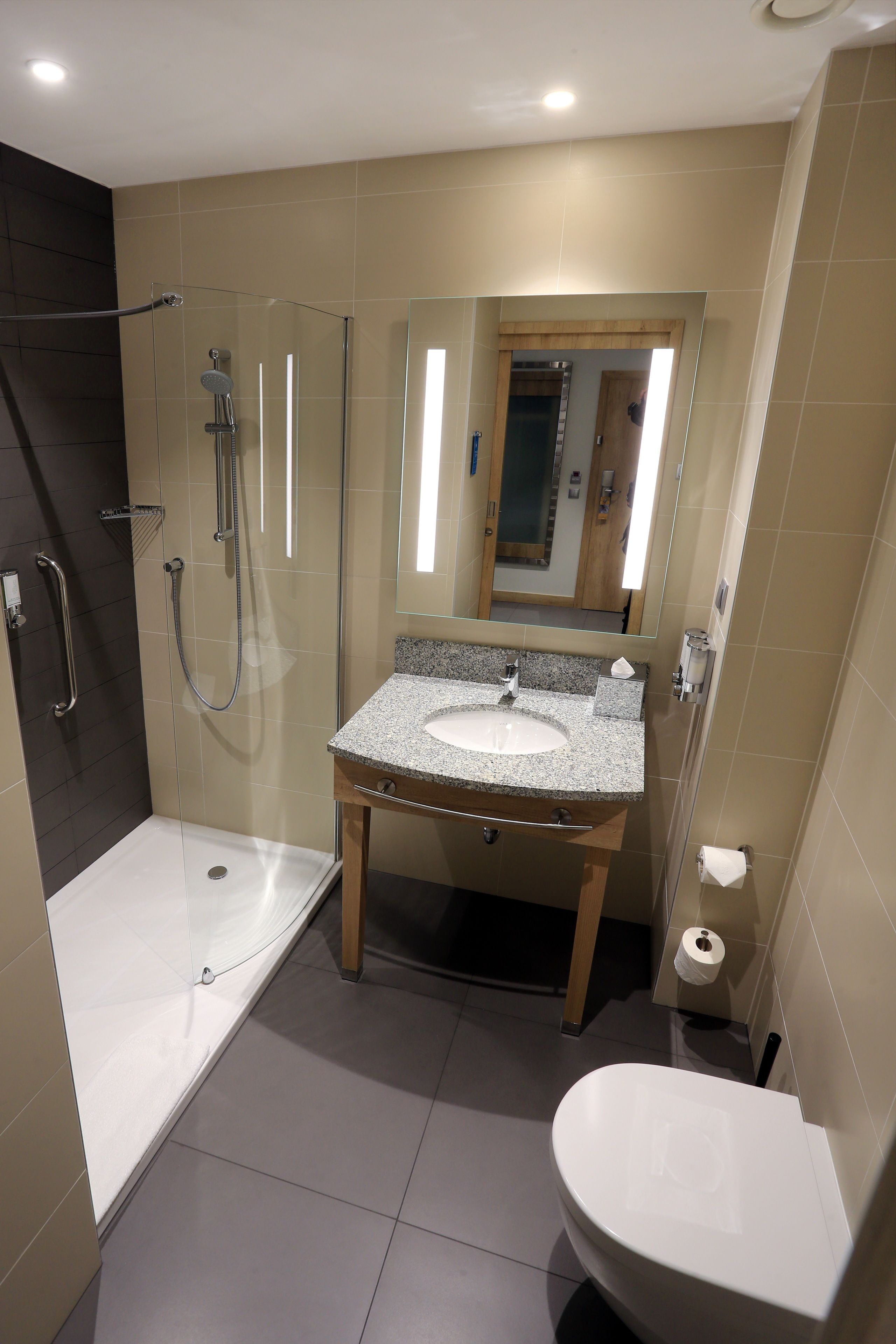 A modern bathroom with a glass-enclosed shower, a sink with a marble countertop, and a toilet.