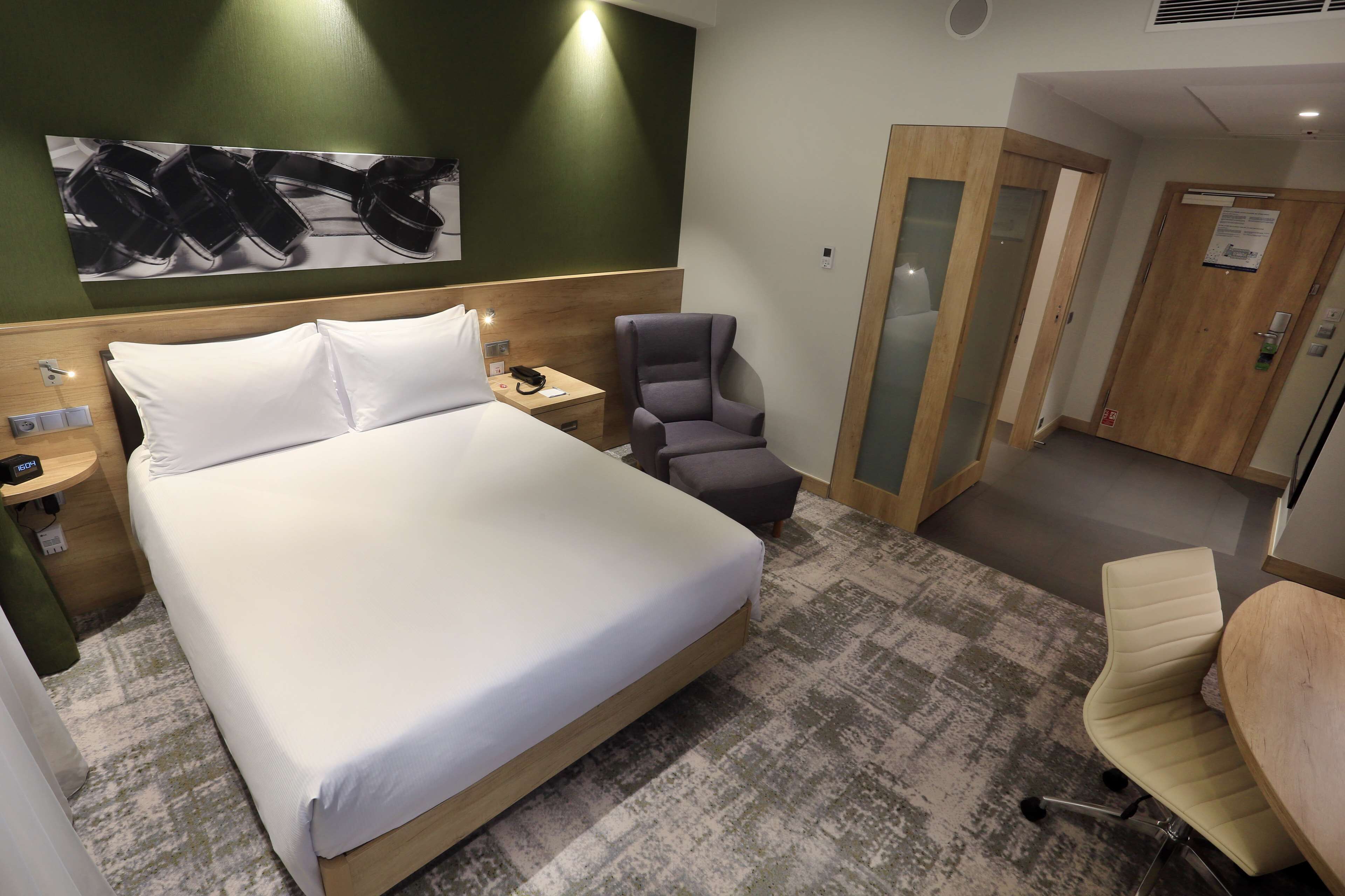 Ett hotellrum med en säng, en stol, ett skrivbord och ett litet bord.