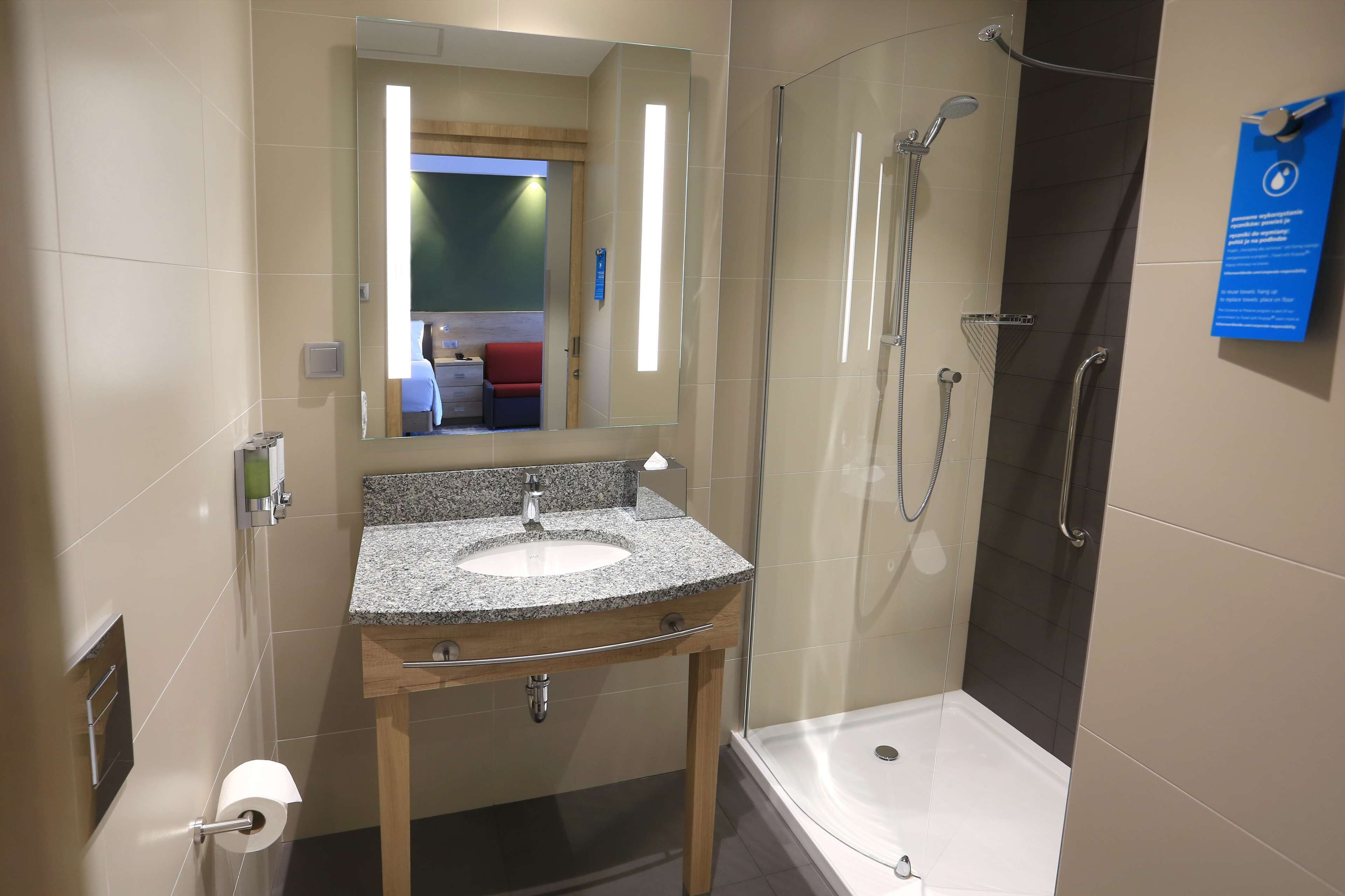 A modern bathroom with a granite sink, a mirror, a shower with a glass door, and a sign on the wall.