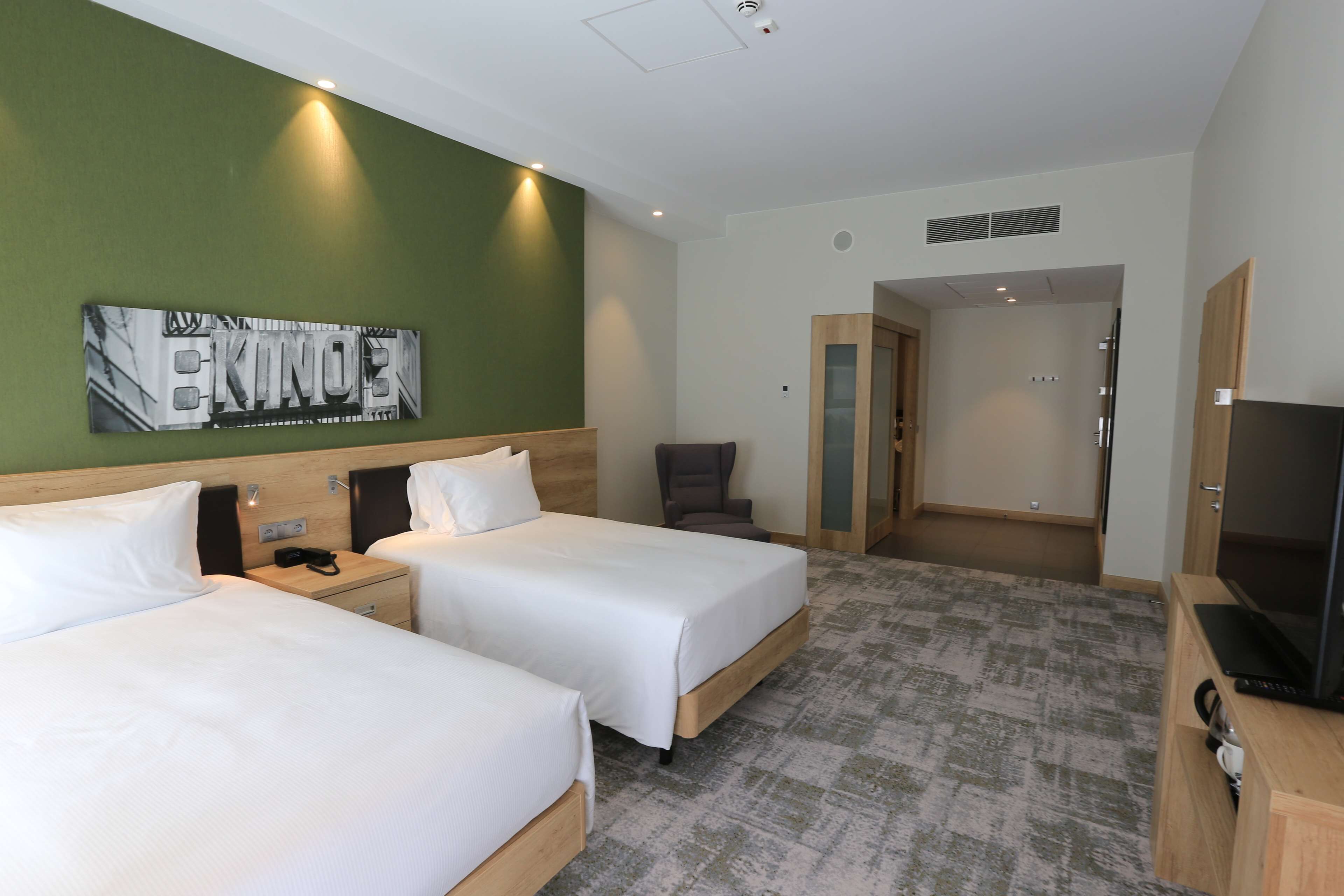 Quarto de hotel com duas camas, televisão, escrivaninha e uma cadeira.