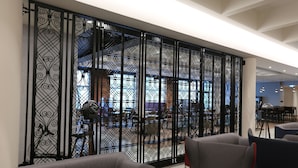 Un intérieur moderne agrémenté d’une cloison décorative en métal noir, de canapés gris et, au fond, d’un aperçu d’un coin repas.