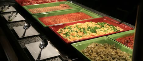 A buffet with various dishes in green and red trays.