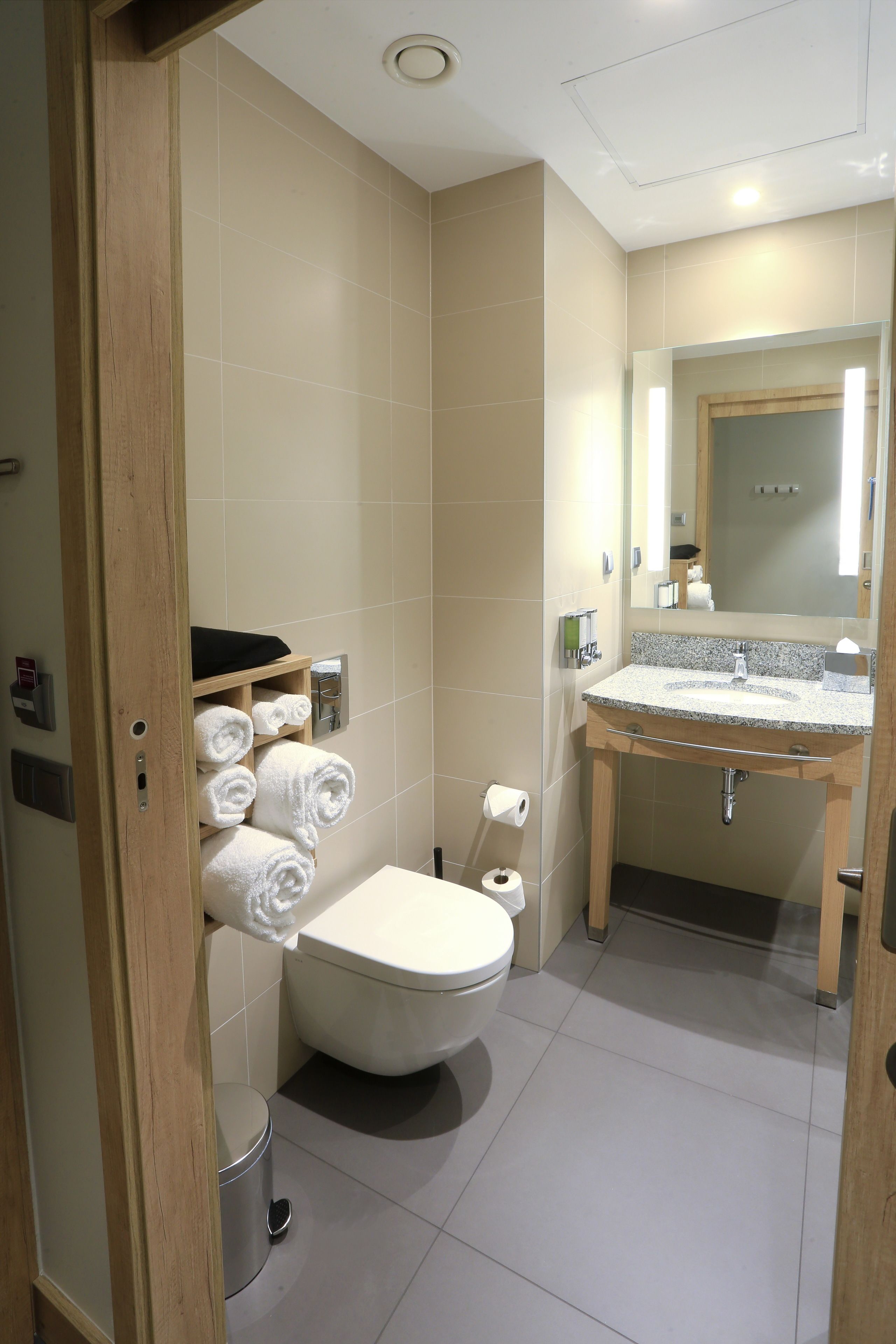 A bathroom with a toilet, sink, and a towel rack with neatly folded towels.