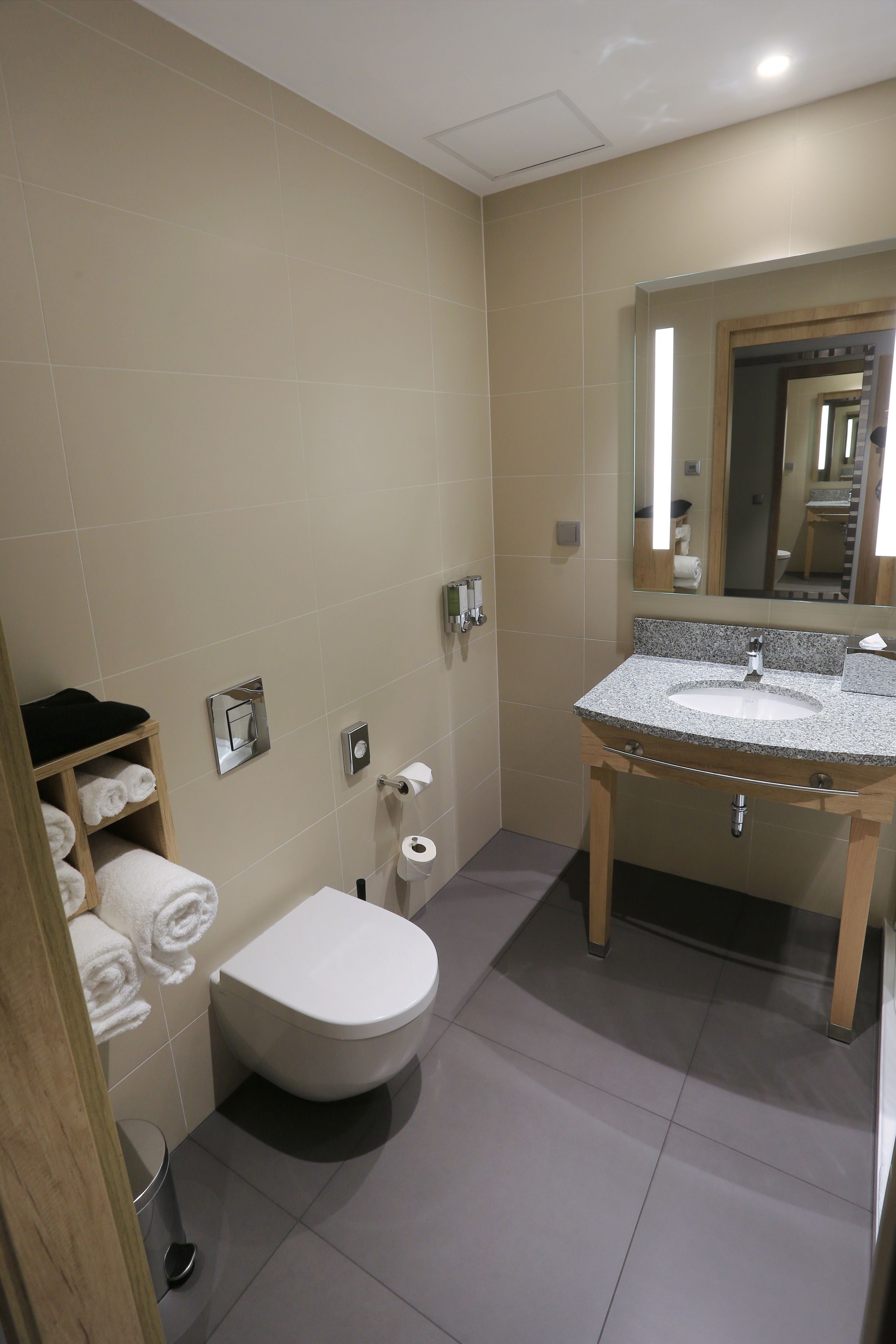 Une salle de bain moderne équipée de toilettes, d’un lavabo et d’un porte-serviettes.