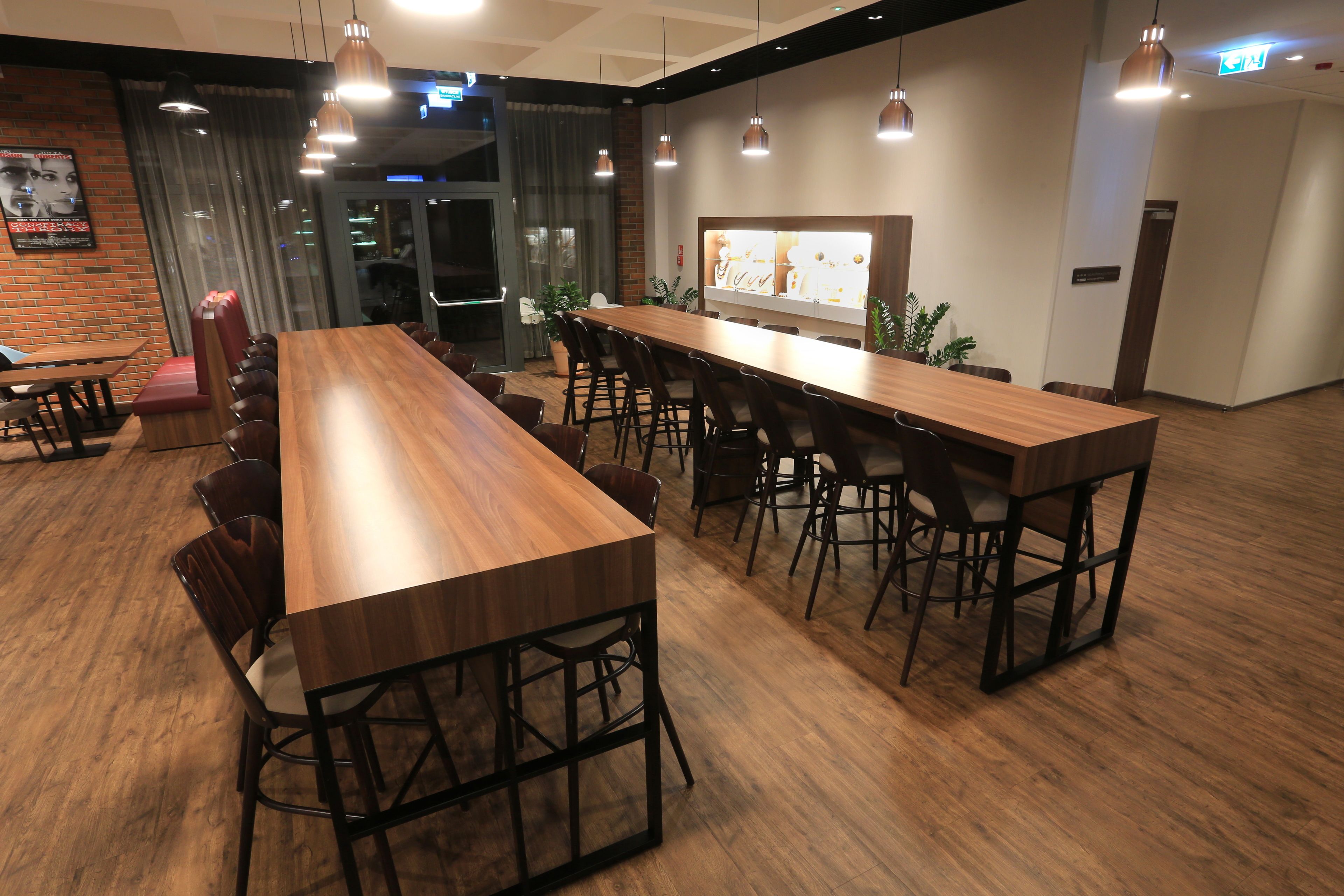 A modern restaurant with a long wooden bar and multiple seating areas, including booths and high tables.