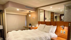 A hotel room with a large bed, a desk, a chair, a mirror, and a small wooden side table. - Hotel Cle Reforma Insurgentes (Mexico City)