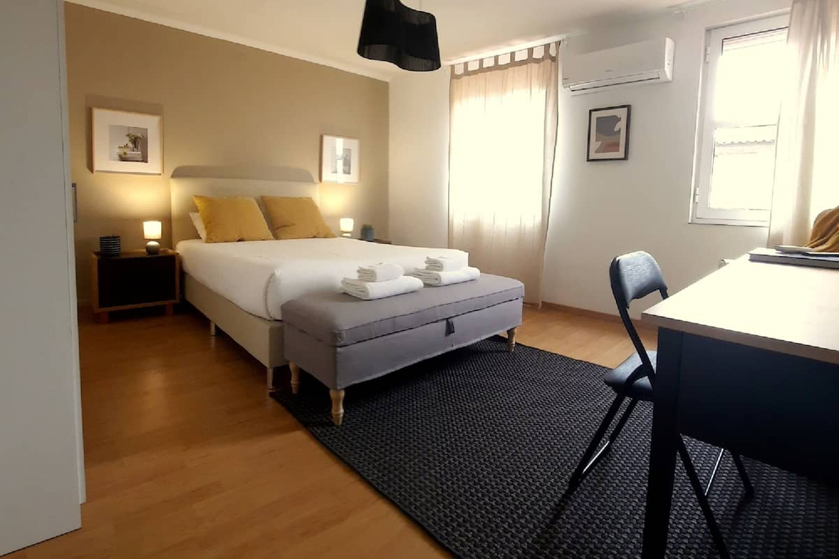 A bedroom with a bed, bedside tables, a desk, and a chair.