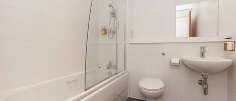 Une salle de bain moderne avec une douche à parois de verre, des toilettes blanches et un lavabo surmonté d’un miroir.