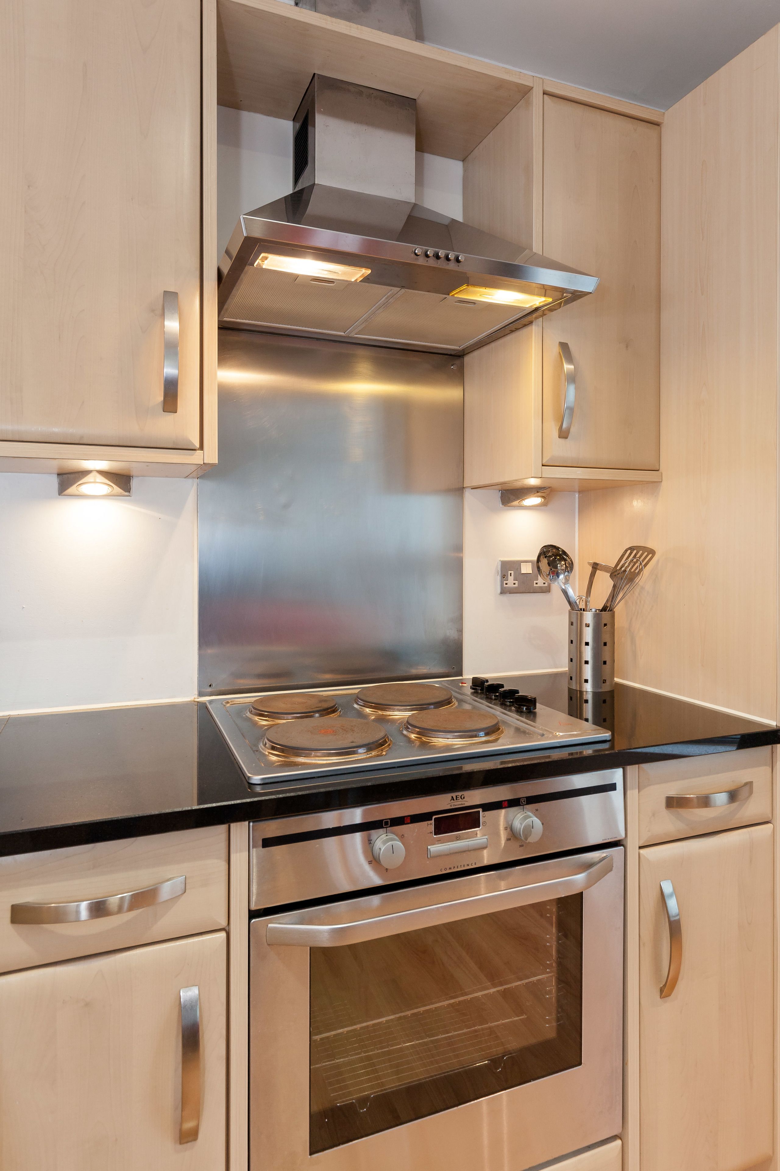 A modern kitchen with stainless steel appliances, wooden cabinets, and a black countertop.