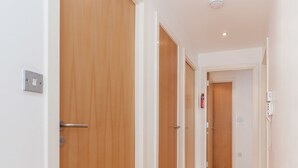 Un couloir avec des portes en bois et un mur blanc.