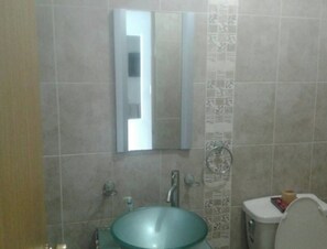 A bathroom with a large mirror, a sink, and a toilet. - Casa Lupita (Mazatlán)