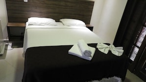 Une chambre d’hôtel avec un grand lit, une tête de lit en bois et une couvre-lit noire.