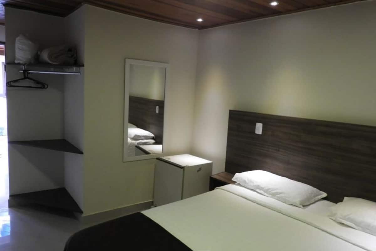 A bedroom with a bed, a bedside table, a mirror, and a wardrobe.