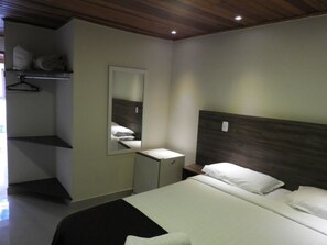 A bedroom with a bed, a bedside table, a mirror, and a wardrobe.
