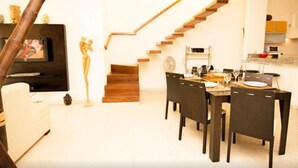 A modern living room with a dining area, a staircase, and a kitchen. - Las Olas family Townhome Apartments (Playa del Carmen)