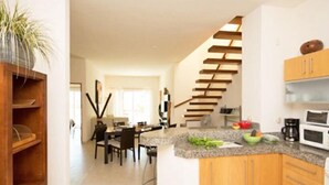 A modern kitchen with a granite countertop, wooden cabinets, and a built-in stove. - Las Olas family Townhome Apartments (Playa del Carmen)