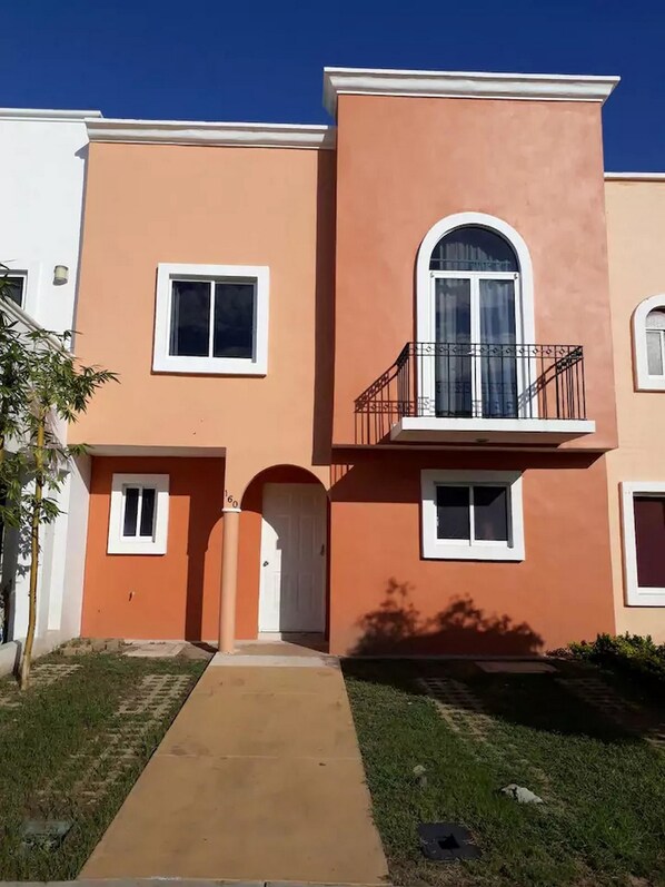 A two-story building with a central entrance, a small balcony with a railing, and a door with a number '60' above it.