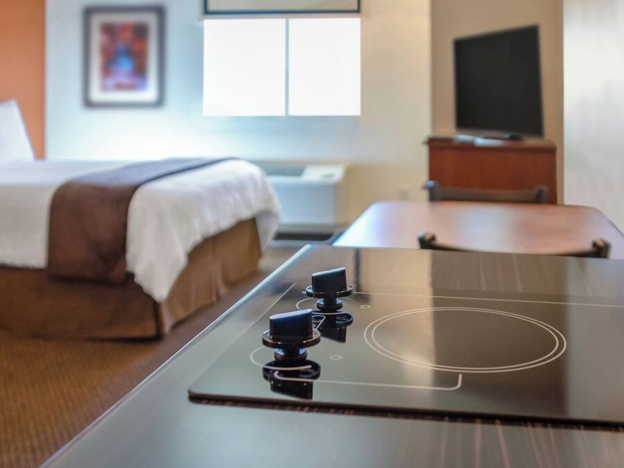 Quarto de hotel moderno com cama, televisão de tela plana e fogão embutido.