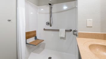 Una ducha con un banco, un perchero y un lavabo con encimera color beige.