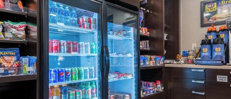 Un réfrigérateur à boissons rempli de diverses boissons, une machine à café et des en-cas.