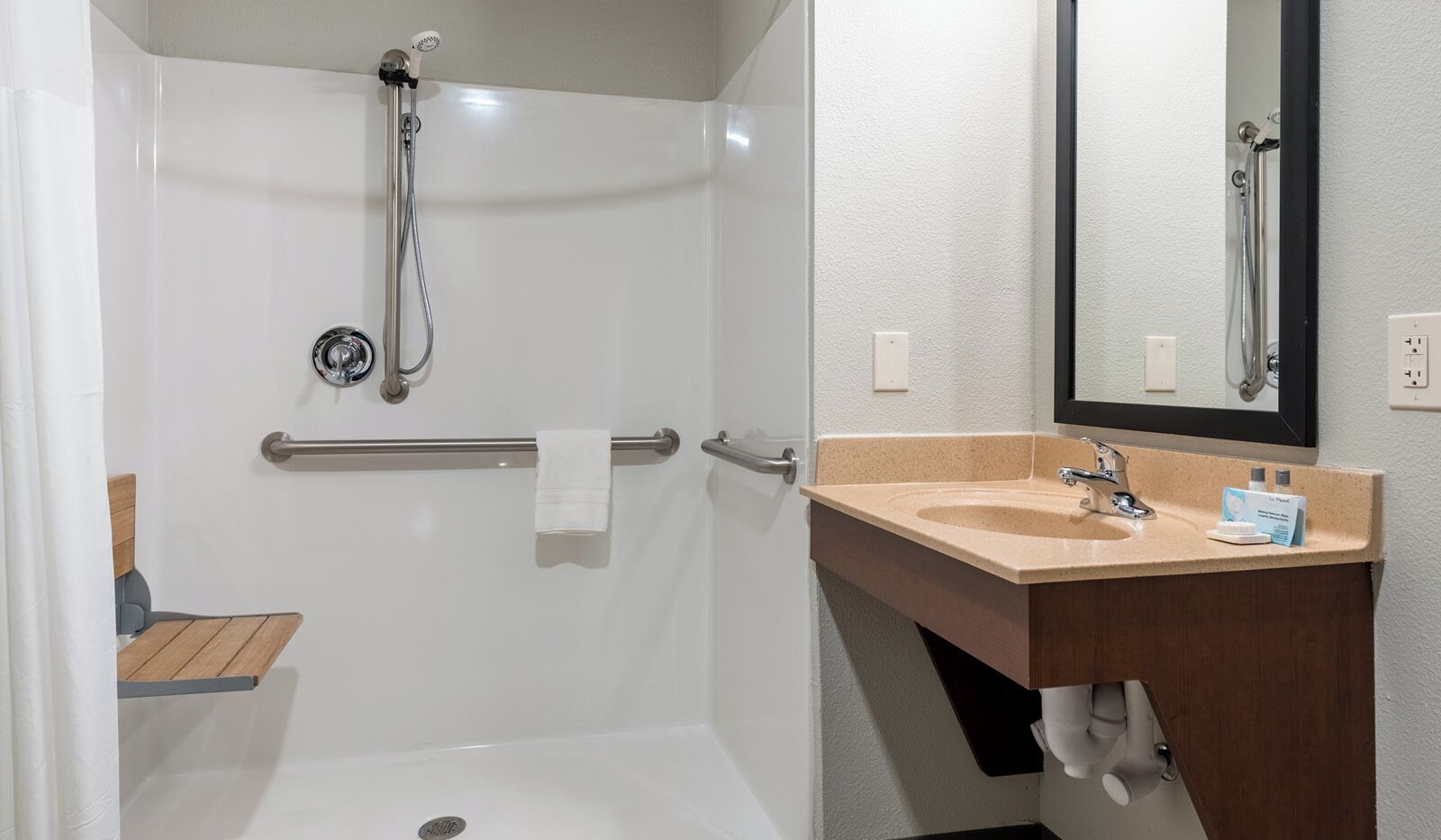 A bathroom with a shower, a sink, and a towel rack.