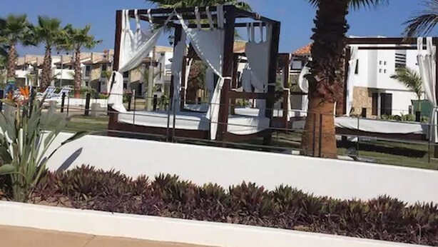 Un resort con piscina, palmeras y un edificio de fachada blanca.