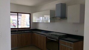 Una cocina con armarios de madera, estufa a gas, horno y ventana con vistas a edificios.