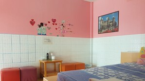 A bedroom with a bed, two red and a purple bench, a small table with bottles, and a picture of a castle on the wall. - Wanjai Resort (Warin Chamrap)
