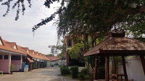 A courtyard with a gazebo, a covered walkway, and buildings with red-tiled roofs. - Wanjai Resort (Warin Chamrap)