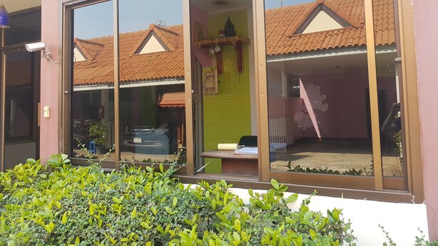 A building with large windows, a tiled roof, and a security camera. - Wanjai Resort (Warin Chamrap)
