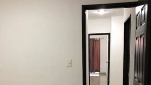 A bedroom with a bed, a door leading to another room, and a hallway. - Casita Selin C (Mazatlán)