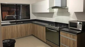 A modern kitchen with a gas stove, oven, microwave, and wooden cabinets. - Casita Selin C (Mazatlán)