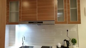 A kitchen with wooden cabinets, a stainless steel sink, and a coffee maker. - Goodview Apartment Hotel (Changsha)