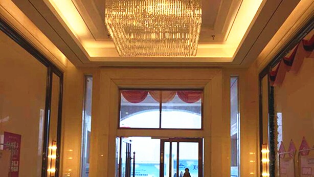 A hotel lobby with a reflective floor, a large chandelier, and a view of the beach through the entrance. - Goodview Apartment Hotel (Changsha)