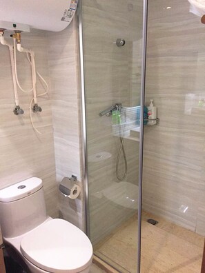 A bathroom with a toilet, a glass-enclosed shower, and a toilet paper holder. - Goodview Apartment Hotel (Changsha)