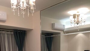 A bedroom with a bed, a large mirror, a chandelier, and an air conditioning unit. - Goodview Apartment Hotel (Changsha)